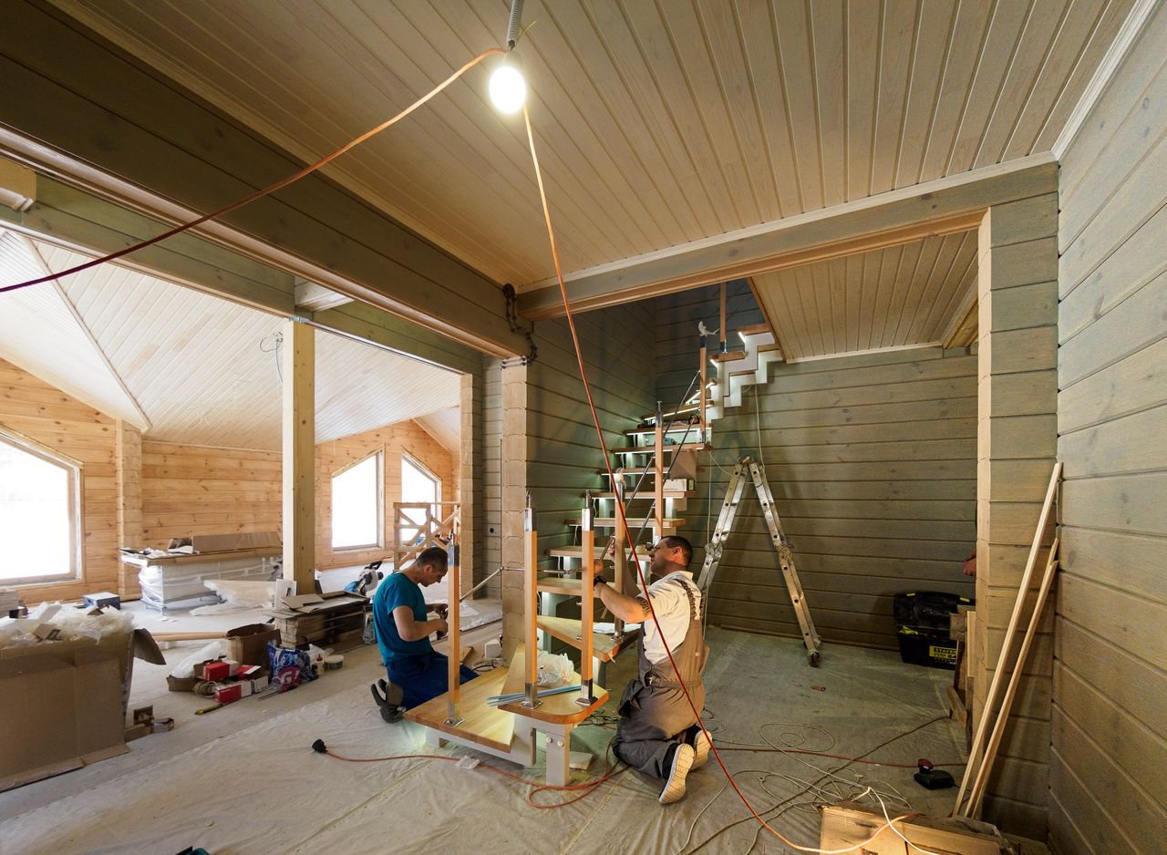 Free Carpenters skillfully assembling a modern wooden staircase inside a newly constructed home interior. Stock Photo